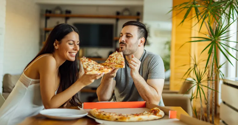 Woman enjoying flexible intermittent fasting with pizza night - cheat days can fit into healthy eating patterns