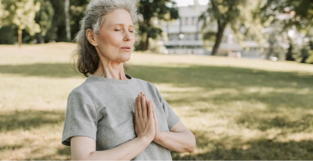 Woman over 50 meditating in park embracing intermittent fasting for health and wellness