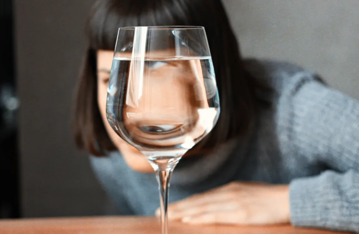Woman drinking water contemplating water fasting schedule and potential health risks before starting